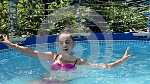 Happy girl child swim in outdoor swimming pool showing v sign victory hand gesture, summer