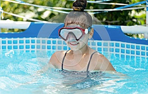 Happy girl child wear swimming mask in outdoor pool in summer, swim