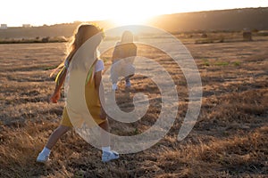 Happy girl child in yellow dress runs to her mom in autumn field