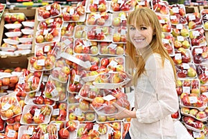 Happy girl chooses packed apples in store photo