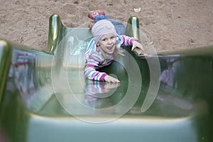 Happy girl climbing on children's slide