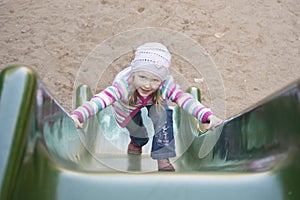 Happy girl climbing on children's slide