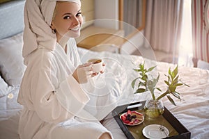 Happy Girl with a Cup of Coffee. Home Style Relaxation Woman Wearing Bathrobe and Towel after Shower. Spa Good Morning