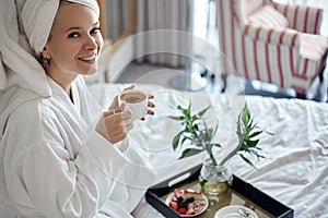 Happy Girl with a Cup of Coffee. Home Style Relaxation Woman Wearing Bathrobe and Towel after Shower. Spa Good Morning