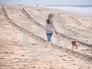 Happy girl with cute dog running on the beach on vacation