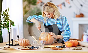 Happy girl is cutting  pumpkin and is preparing for holiday Halloween