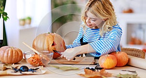 Happy girl is cutting  pumpkin and is preparing for holiday Halloween