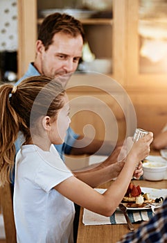 Happy, girl and dad together with breakfast on table for nutrition, eating or sharing. Hungry, man and kid in home