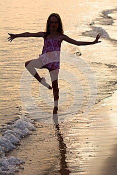 Happy girl dancing on the beach at the sunset time