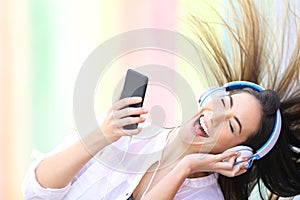Happy girl dancing listening to music holding phone