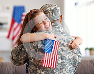 Happy girl daughter with american flag hugging father came back from US army