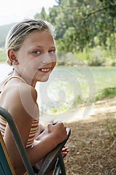 Happy Girl On Deckchair By Lake