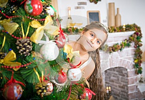 Happy girl decorates Christmas tree.