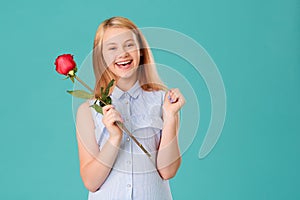 A happy girl is delighted with a gift-a red rose