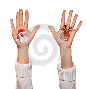 Happy girl demonstrating Christmas symbols painted on hands. Santa Claus and reindeer