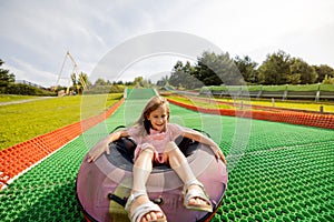 Happy girl descends in inflatable sledding tube at amusement park