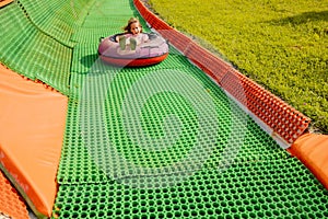 Happy girl descends in inflatable sledding tube at amusement park