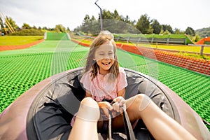 Happy girl descends in inflatable sledding tube at amusement park