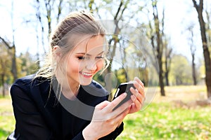 Happy girl with disheveled hair looking into smartphone smiling