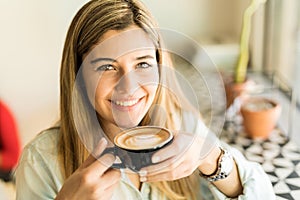 Happy girl drinking a cup of cappuccino