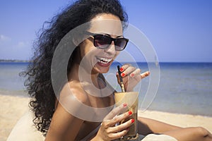 Happy girl drinking iced coffee on the beach
