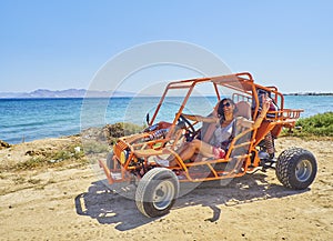 A happy girl driving a Buggy on a beach dune. Kos island. South