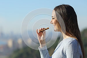 Happy girl eating a snack bar in the city outskirts photo