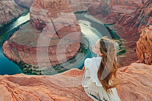 Happy girl on the edge of the cliff at Horseshoe Band Canyon in Paje, Arizona. Adventure and tourism concept. Beautiful