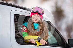 Happy girl enjoying winter sports  cheerful portrait of a girl in the car and in a ski mask  arrived at the ski resort  tourist