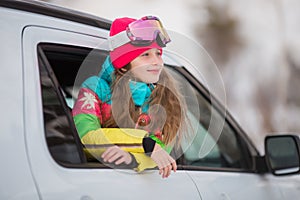 Happy girl enjoying winter sports, cheerful portrait of a girl in the car and in a ski mask, arrived at the ski resort, tourist