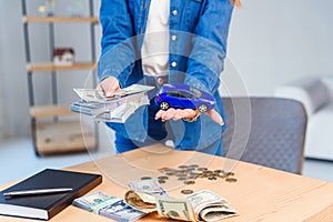 Happy girl in eyeglasses holds a sum of money in one hand and small model of her future car in another hand.