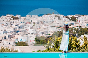 Happy girl feel freedom relaxing on the edge of pool with amazing view on Mykonos, Greece