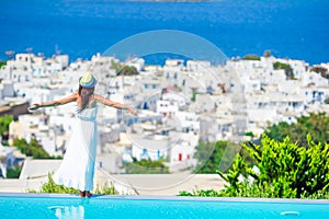 Happy girl feel freedom relaxing on the edge of pool with amazing view on Mykonos, Greece