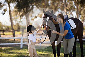 Happy girl and female jockey stroking horse