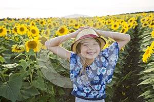 Happy girl on a field of sunflowers on summer sunset