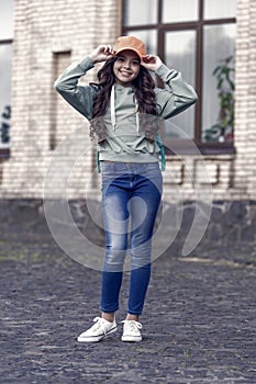 Happy girl fix stylish cap with fashion look wearing casual clothes on urban outdoors, hipster