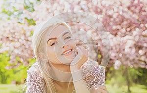 Happy girl with flowers in grass. Cute face of smiling young woman on spring. Dream woman.