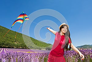 Happy girl flying colorful kite in lavender field