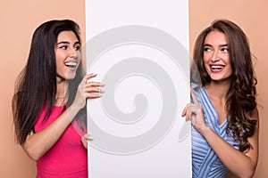 Happy girl friends holding blank advertisement board