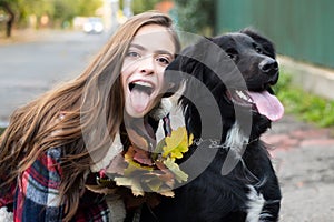 Happy girl gets lovely dog, plays and embraces. Humans and dogs. Girl with tongue embracing puppy dog outdoor.