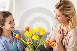 Happy girl giving flowers to mother at home