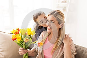 Happy girl giving flowers to mother at home