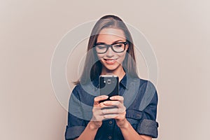 Happy girl in glasses typing sms on gray background