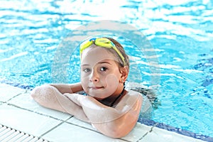 Happy girl with goggles in swimming pool