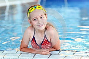 Happy girl with goggles in swimming pool