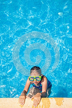 Happy girl with goggles in swimming pool