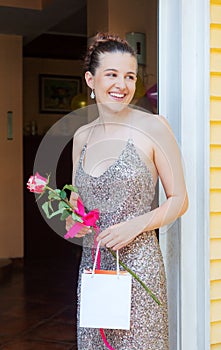 Happy Girl Graduate is Standing on the Porch Smiling Holding Empty Bag and Rose