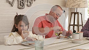 Happy girl and grandfather having breakfast together at home