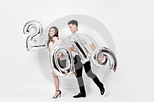 Happy girl and guy dressed in a stylish smart clothes are holding balloons in the shape of numbers 2019 on a white