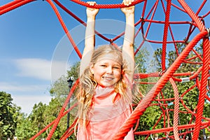 Happy girl hanging on red rope of net outside